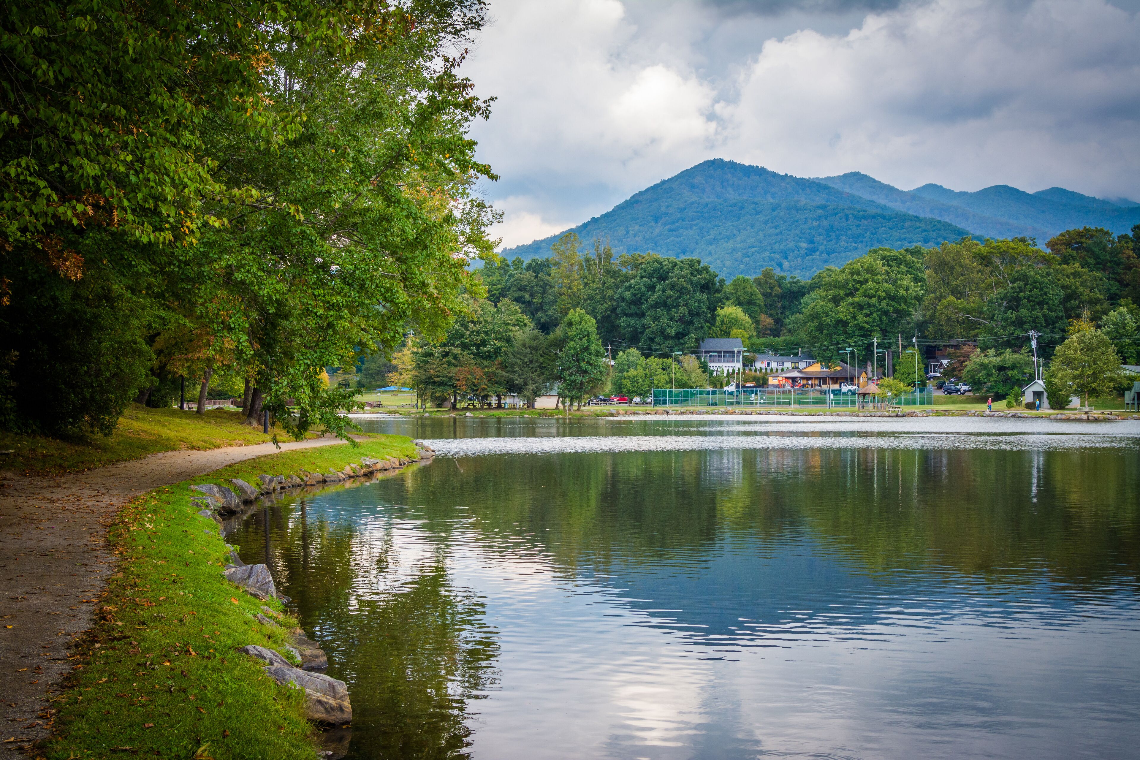 A calm lake surrounded by lush greenery and mountains in the background.