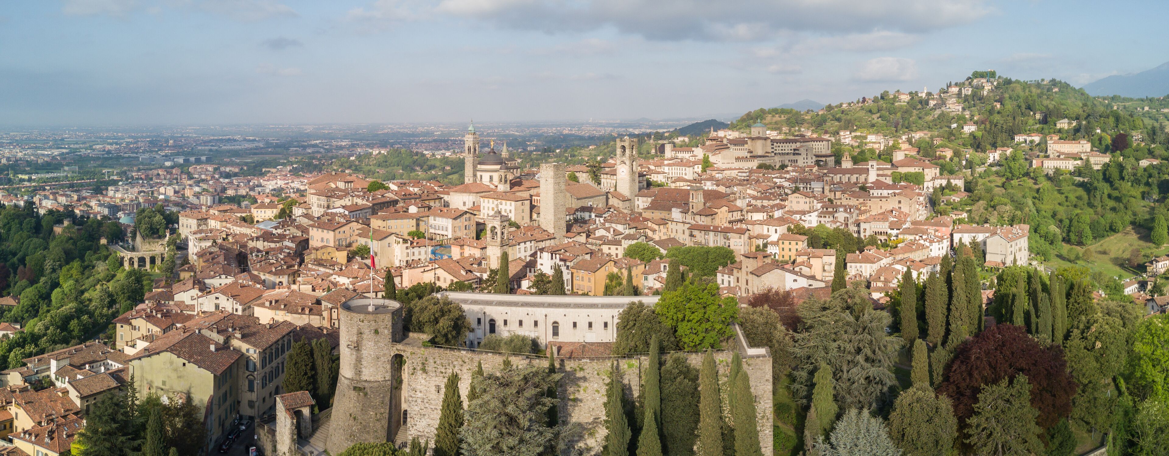 Drone aerial view of Bergamo - Old city (upper town), Italy. Landscape on the city center, the old fortress and its historical buildings during a wonderful blu day