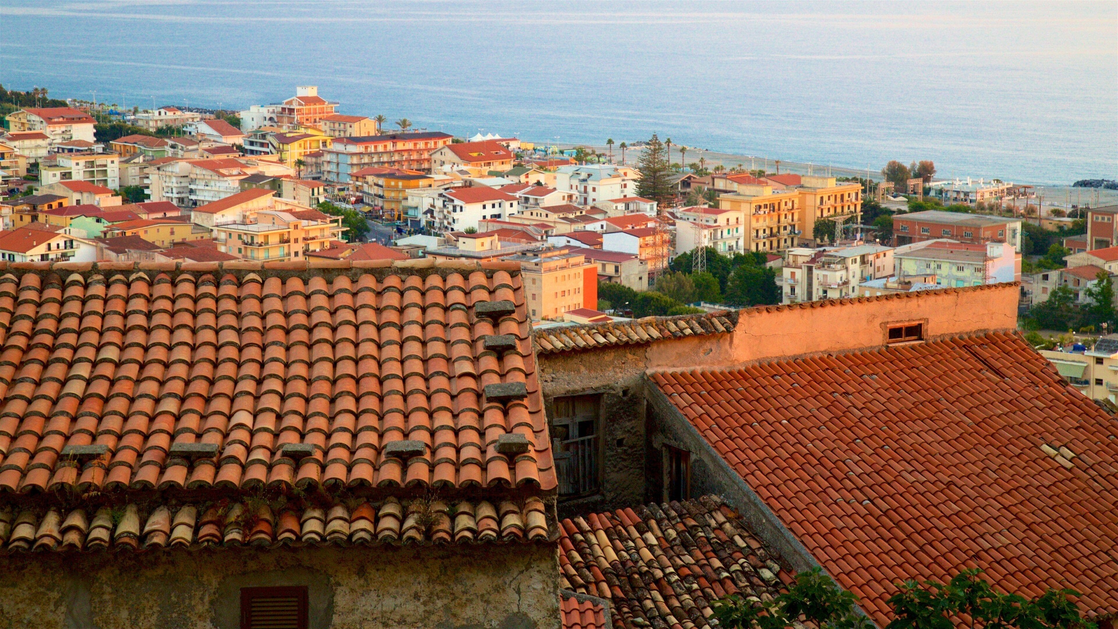 A coastal town with terracotta-roofed buildings and a view of the sea.