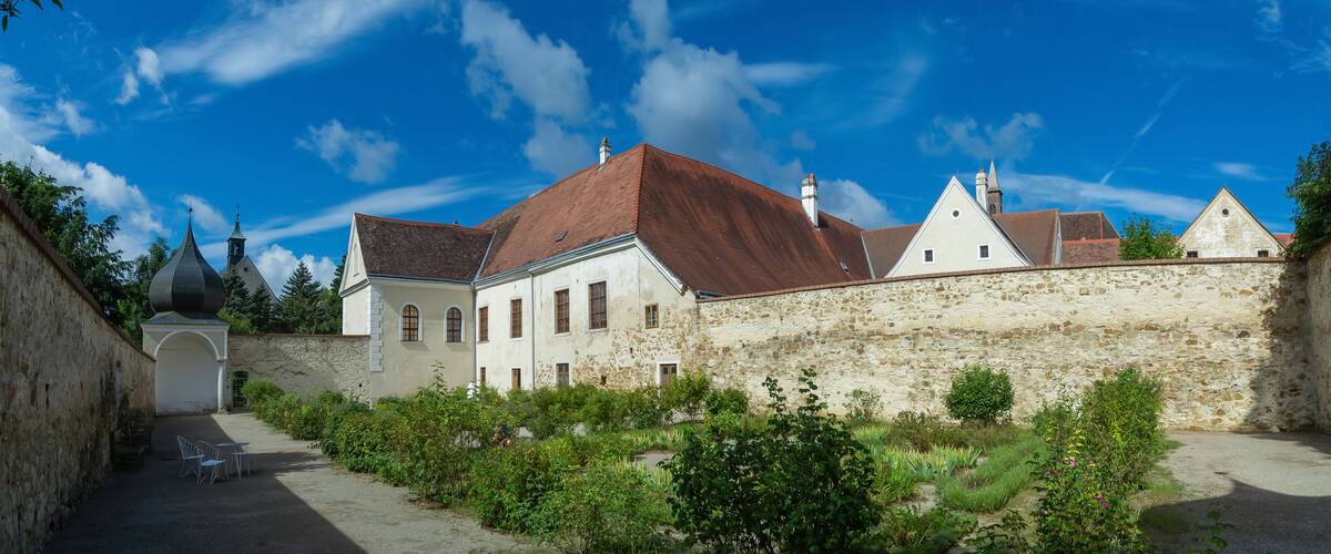 A historic building with a stone wall and a red-tiled roof.