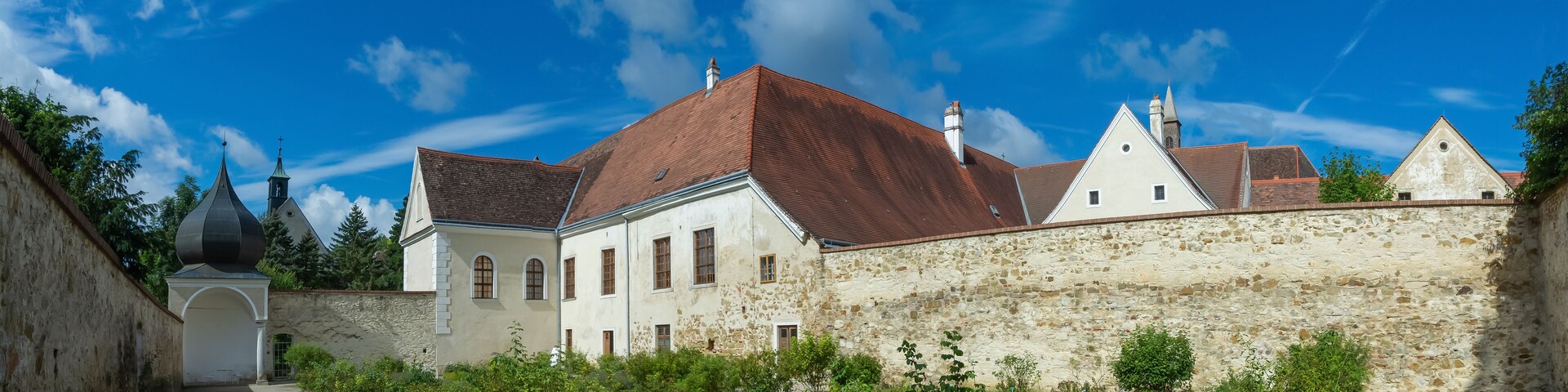A historic building with a stone wall and a red-tiled roof.