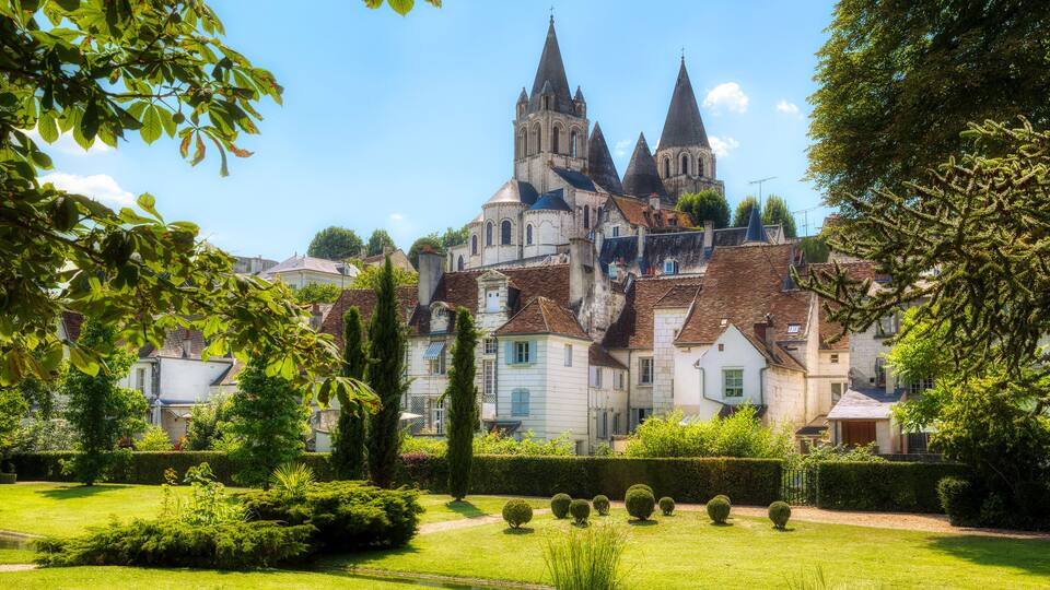 A historic church with multiple spires, surrounded by well-maintained gardens and residential buildings.