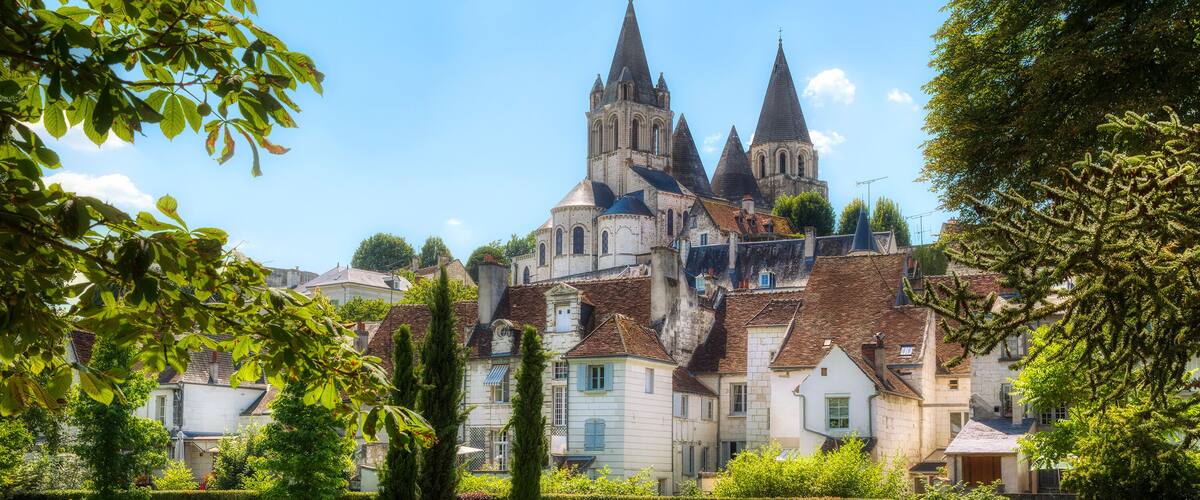 A historic church with multiple spires, surrounded by well-maintained gardens and residential buildings.