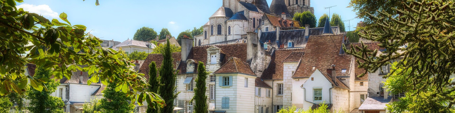 A historic church with multiple spires, surrounded by well-maintained gardens and residential buildings.