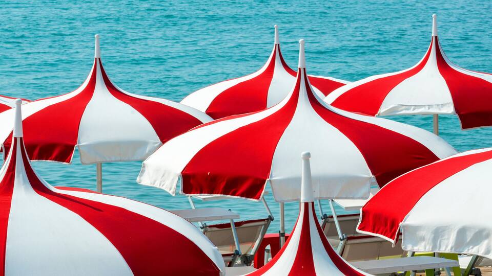 A beach with red and white striped umbrellas.