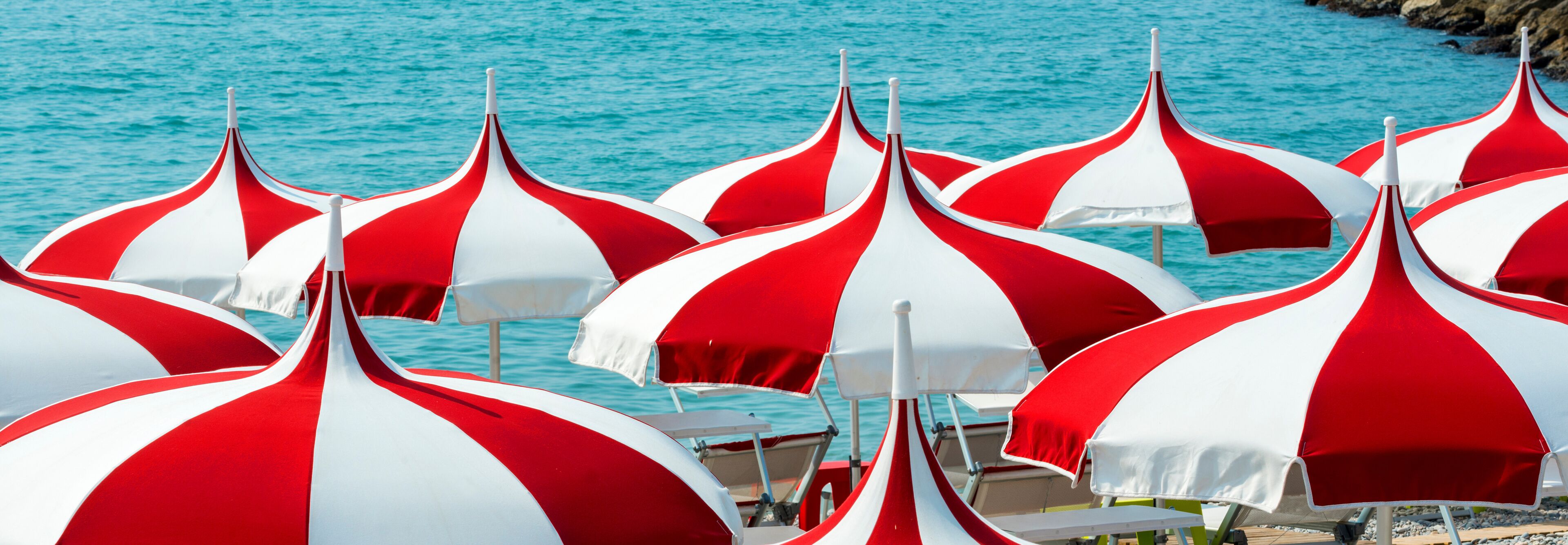 A beach with red and white striped umbrellas.