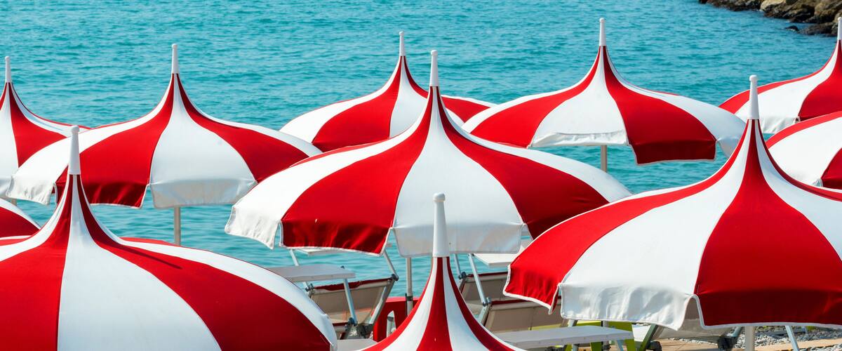 A beach with red and white striped umbrellas.