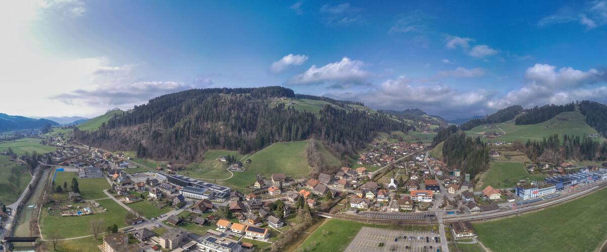 A town nestled in a valley with a railway line, surrounded by hills and forests.