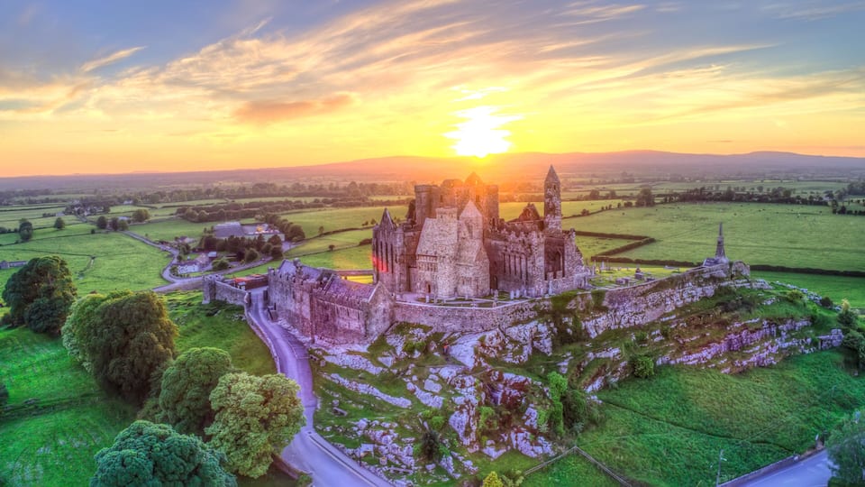 A historic castle surrounded by green fields and a clear sky.