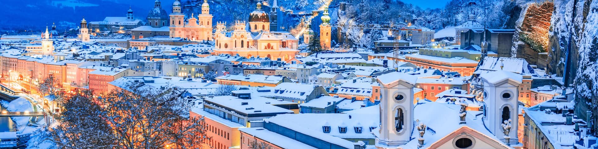 Salzburg, Austria: Winter view of the historic city of Salzburg with famous Festung Hohensalzburg and Salzach river illuminated in beautiful twilight during scenic Christmas time in winte