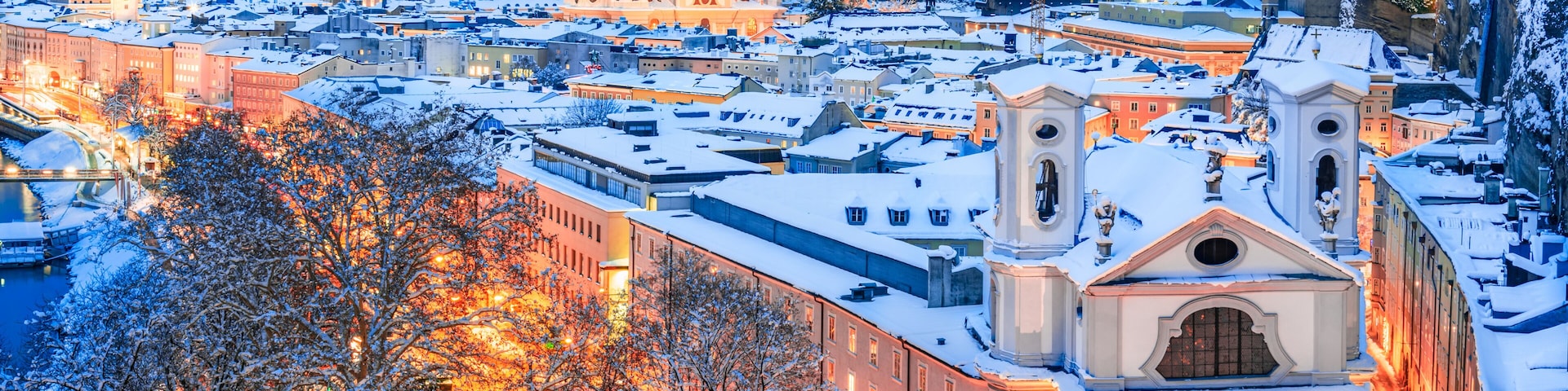 Salzburg, Austria: Winter view of the historic city of Salzburg with famous Festung Hohensalzburg and Salzach river illuminated in beautiful twilight during scenic Christmas time in winte