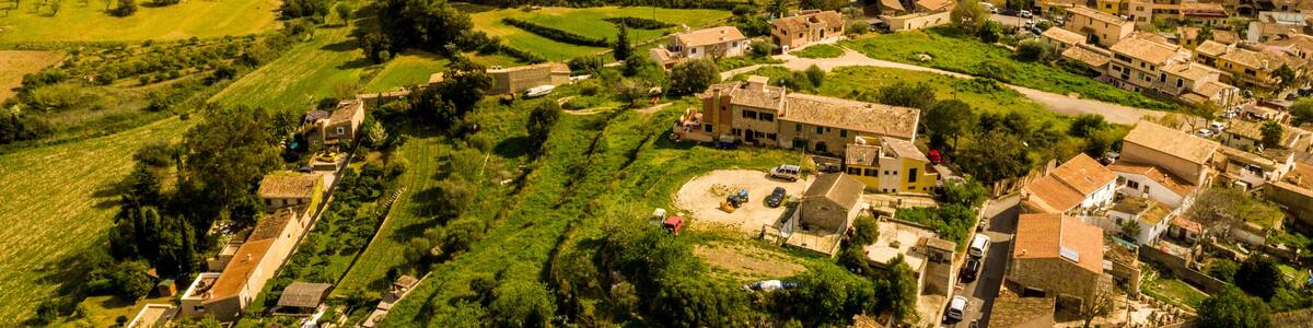 Ländliche Landschaft mit terrassenförmig angelegten Feldern, einem Dorf mit traditioneller Architektur und sanften Hügeln im Hintergrund.