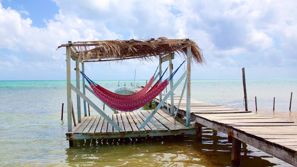 A wooden pier extending into turquoise waters, with a hammock hanging from a thatched structure.
