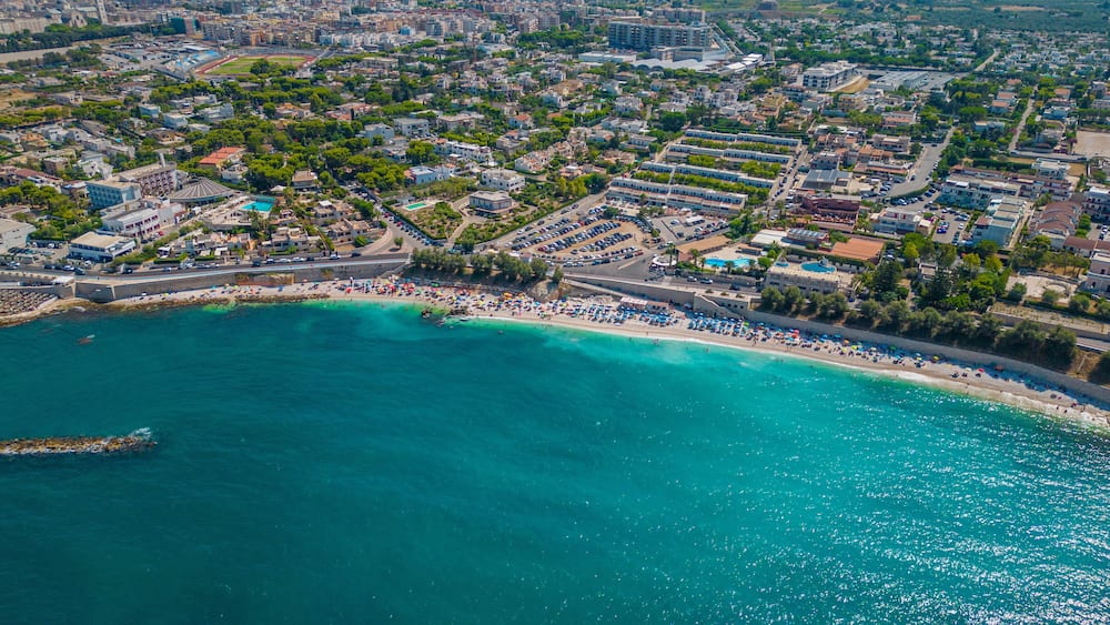 Top view, splendid aerial view of some people relaxing on a beautiful beach washed by the sea. Bisceglie (Apulia, Italy)
