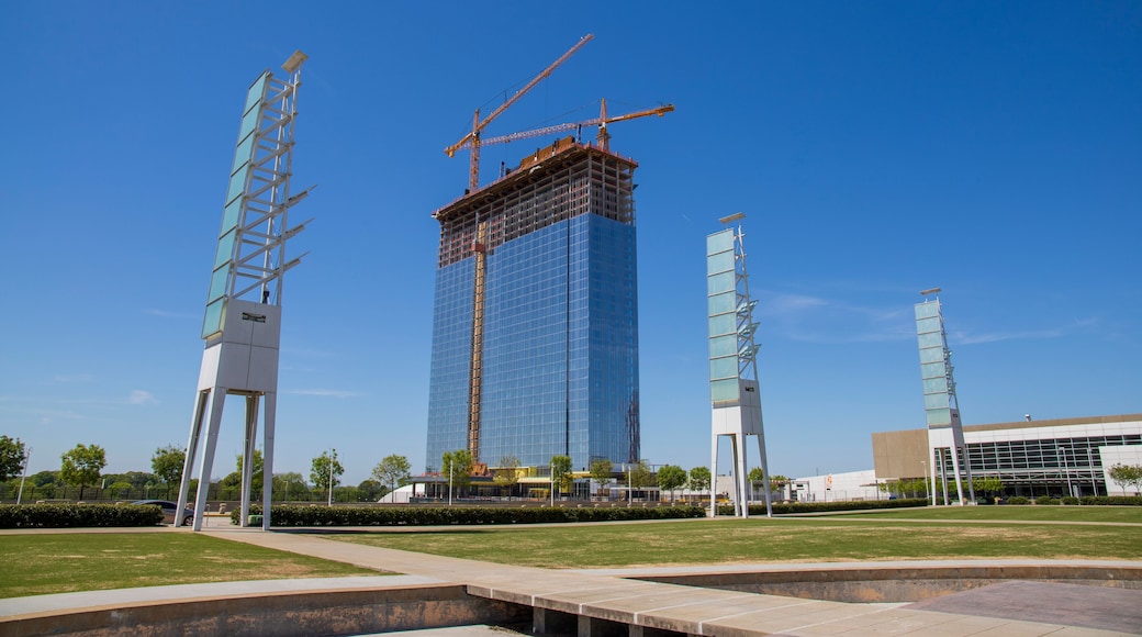 A gorgeous spring landscape at Georgia International Plaza with green trees and grass and a glass skyscraper under construction with tower cranes and a clear blue sky in Atlanta Georgia USA