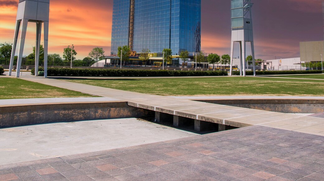 A gorgeous spring landscape at Georgia International Plaza with green trees and grass and a glass skyscraper under construction with tower cranes and powerful clouds at sunset in Atlanta Georgia USA