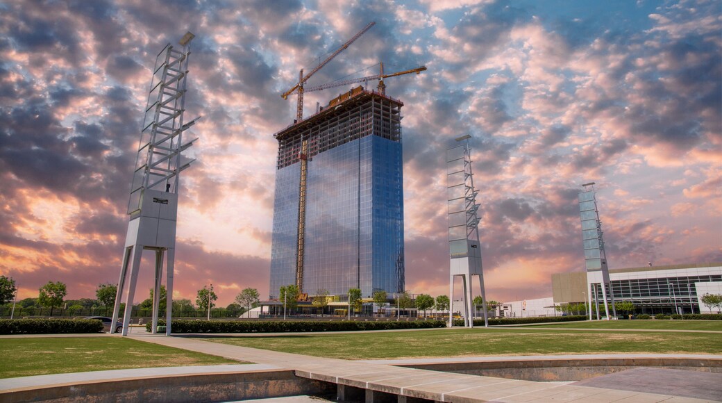 A gorgeous spring landscape at Georgia International Plaza with green trees and grass and a glass skyscraper under construction with tower cranes and powerful clouds at sunset in Atlanta Georgia USA