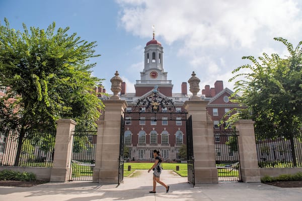 A historic building with a clock tower, a large gate, and a well-maintained lawn.