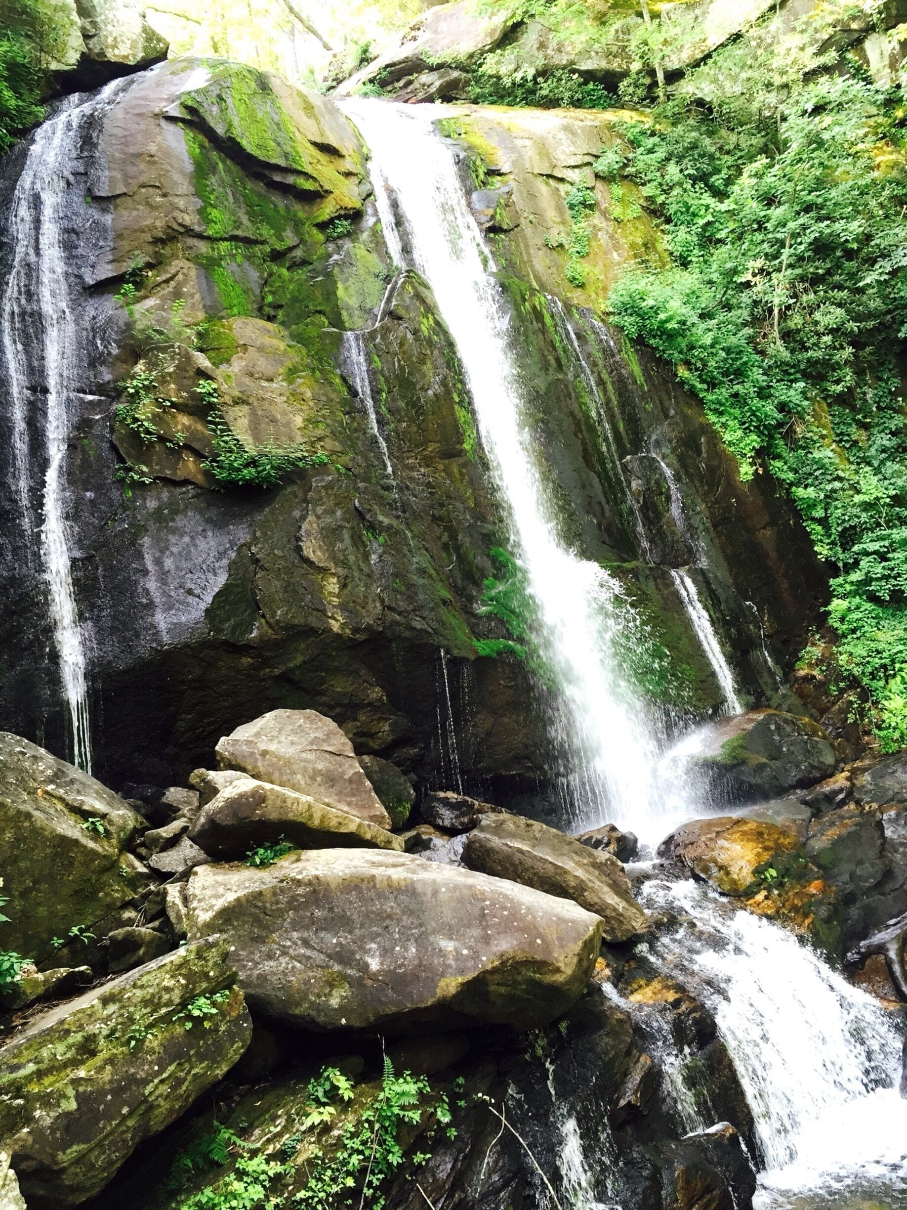 A waterfall cascading over large rocks surrounded by lush greenery.