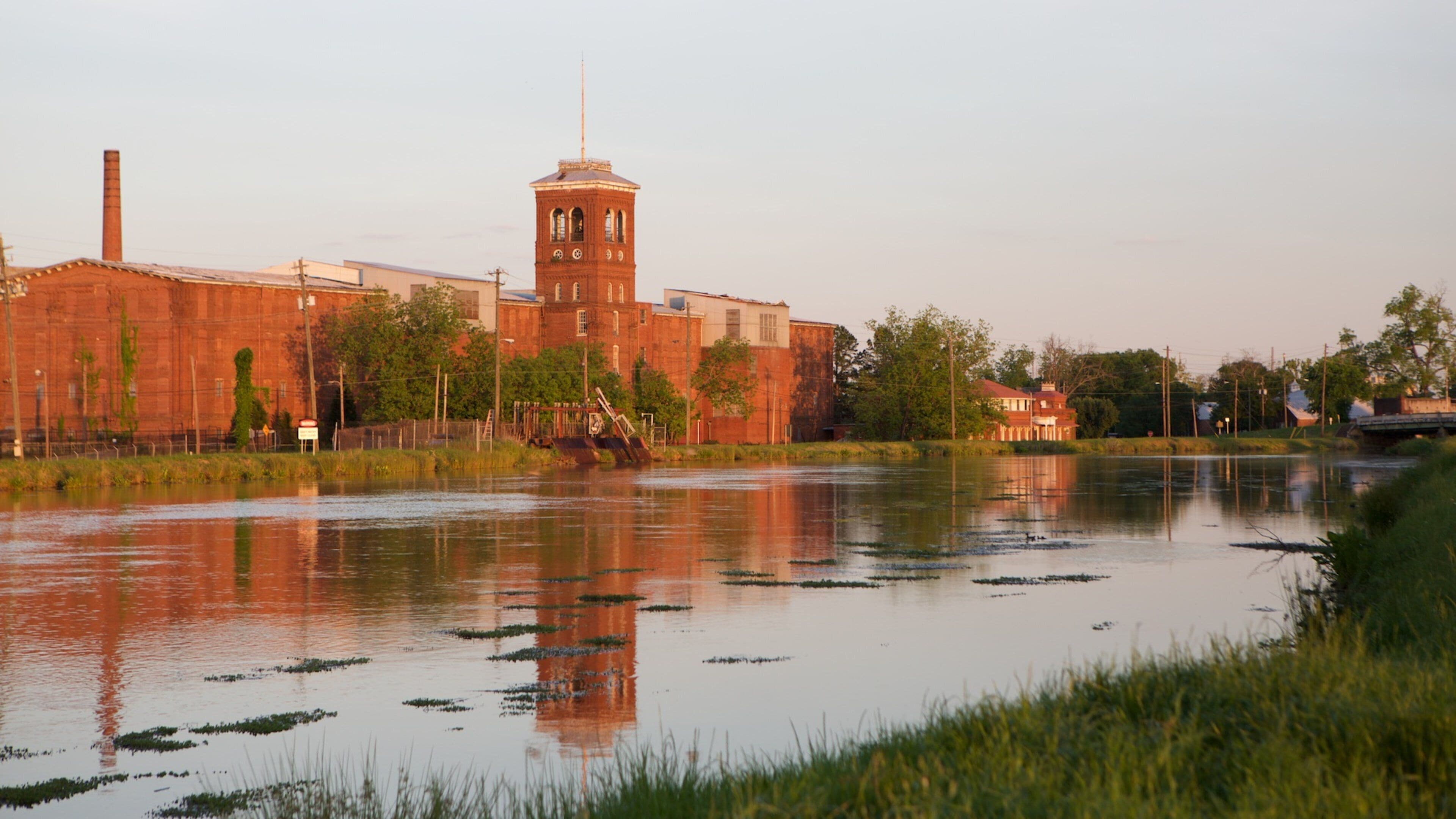 A river with a brick building and a tower in the background.