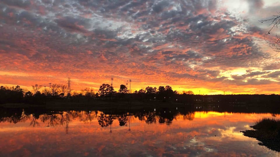 Beautiful sunset over the lake . Many people fishing nearby.