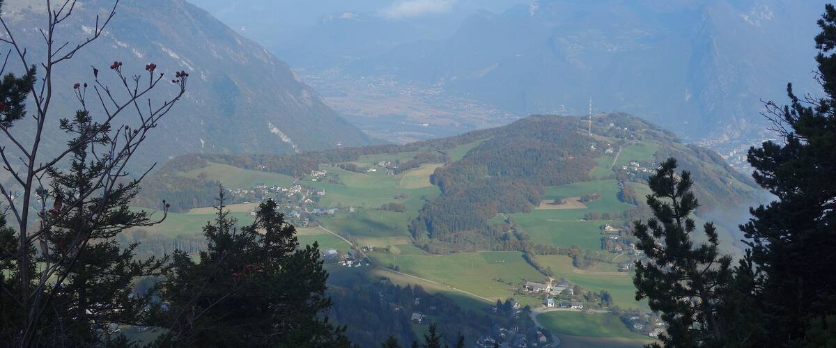 A mountainous landscape with a valley, houses, and a lake.