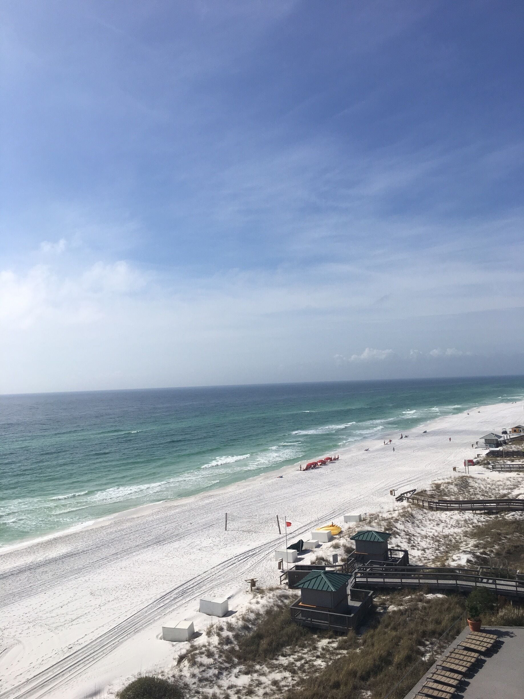 A beach with white sand and a wooden boardwalk.
