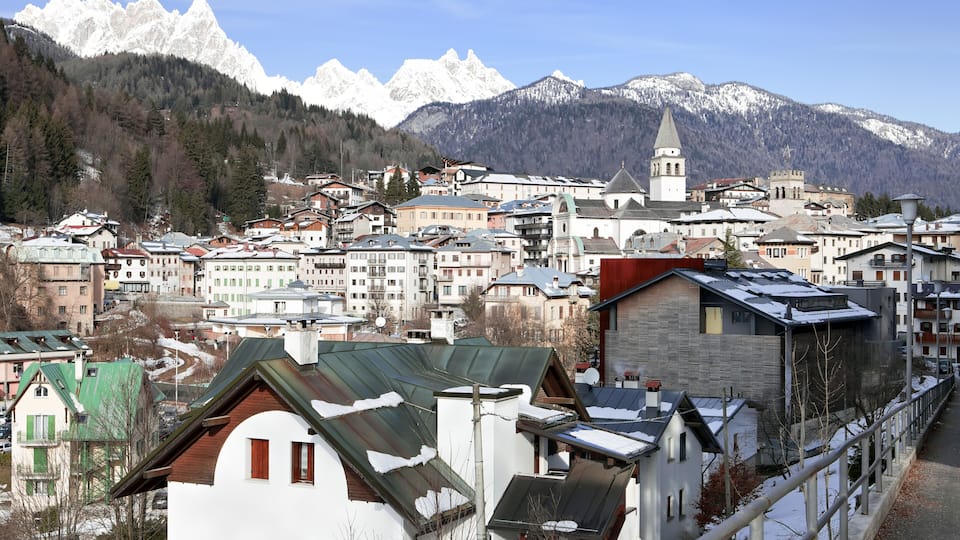 A town with snow-covered buildings and mountains in the background.