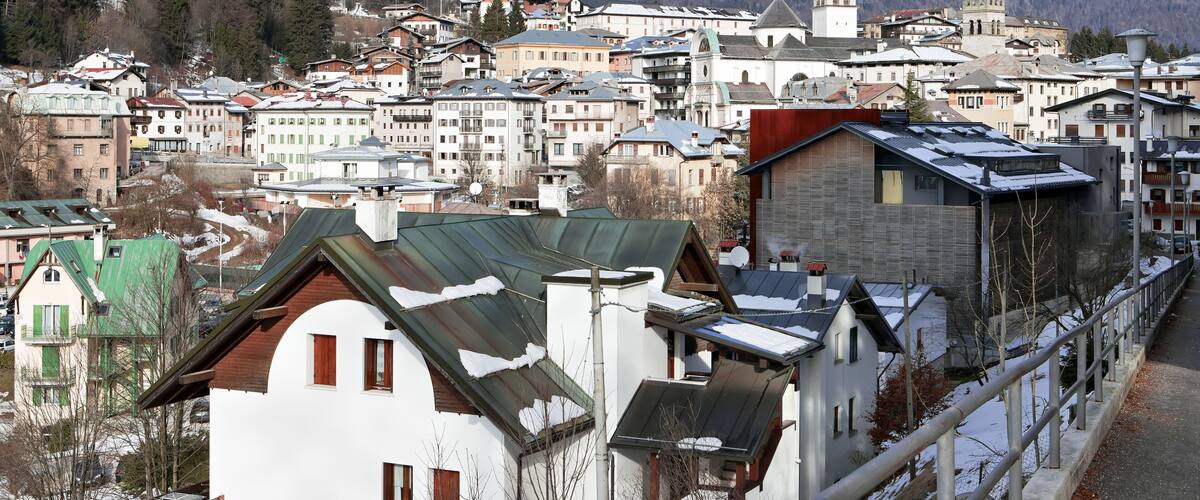 A town with snow-covered buildings and mountains in the background.