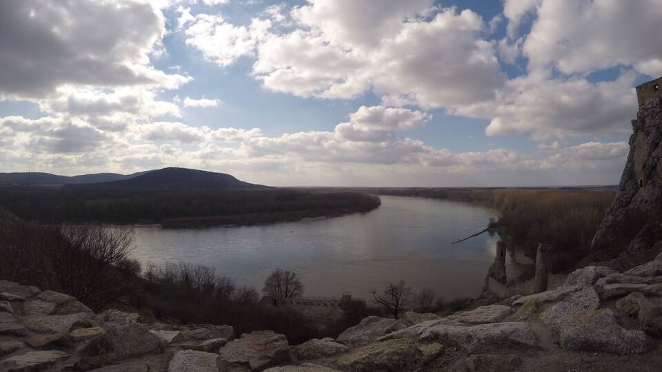 A river with a rocky shoreline and a bridge in the distance.