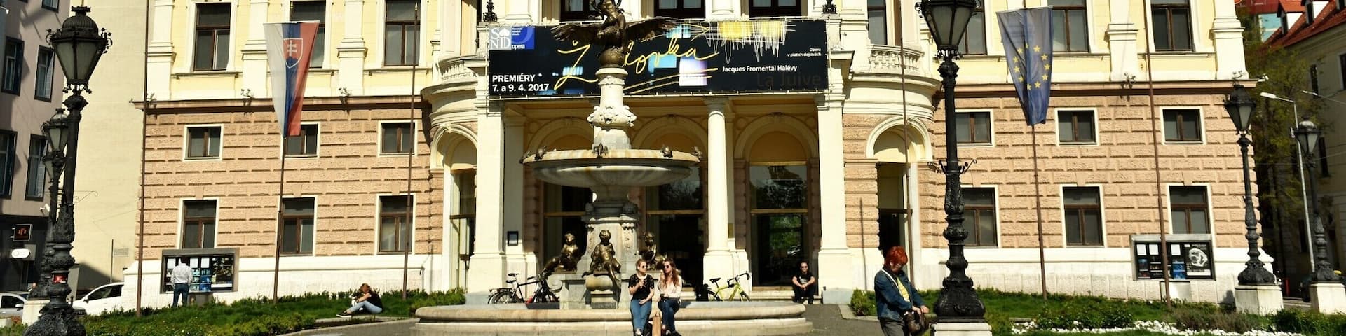 This fountain was designed in 1888 by Bratislava-born V. Tilgner (who also created the putti on the adjacent Opera House). It depicts figures from ancient mythology: an eagle carries the young Ganymede to the top of Mount Olympus, on the order of the Goddess Dia, so that he can serve the Gods. On the upper part of the middle basin there are sculptures of aquatic creatures and, lower down, the central column is surrounded by figures of children holding four types of fish from the River Danube – carp, catfish, sander and pike. From the fishes’ mouths water cascades into the basin. The figures on the fountain were cast by the firm A.M. Beschorner from Budapest