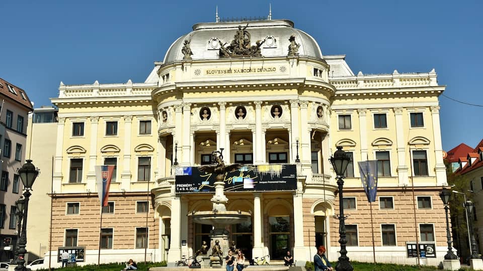 This fountain was designed in 1888 by Bratislava-born V. Tilgner (who also created the putti on the adjacent Opera House). It depicts figures from ancient mythology: an eagle carries the young Ganymede to the top of Mount Olympus, on the order of the Goddess Dia, so that he can serve the Gods. On the upper part of the middle basin there are sculptures of aquatic creatures and, lower down, the central column is surrounded by figures of children holding four types of fish from the River Danube – carp, catfish, sander and pike. From the fishes’ mouths water cascades into the basin. The figures on the fountain were cast by the firm A.M. Beschorner from Budapest