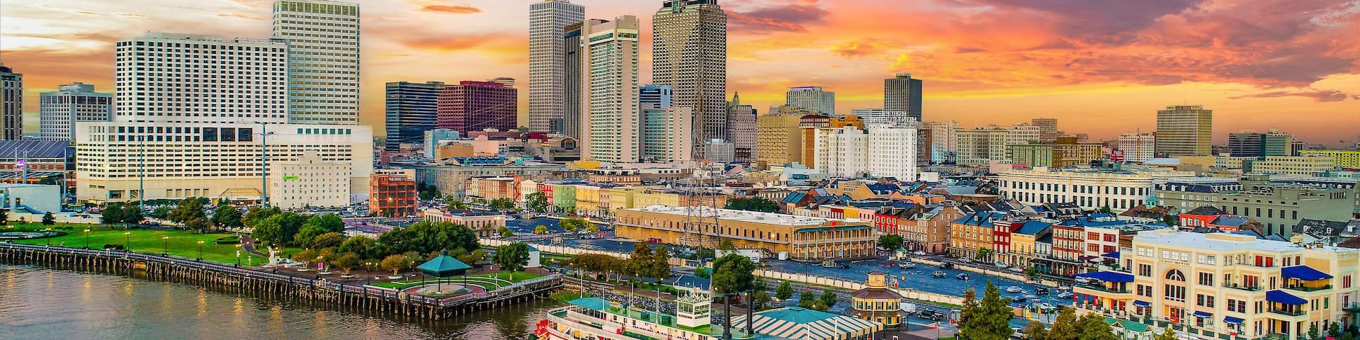A city skyline with tall buildings and a river with a boat.