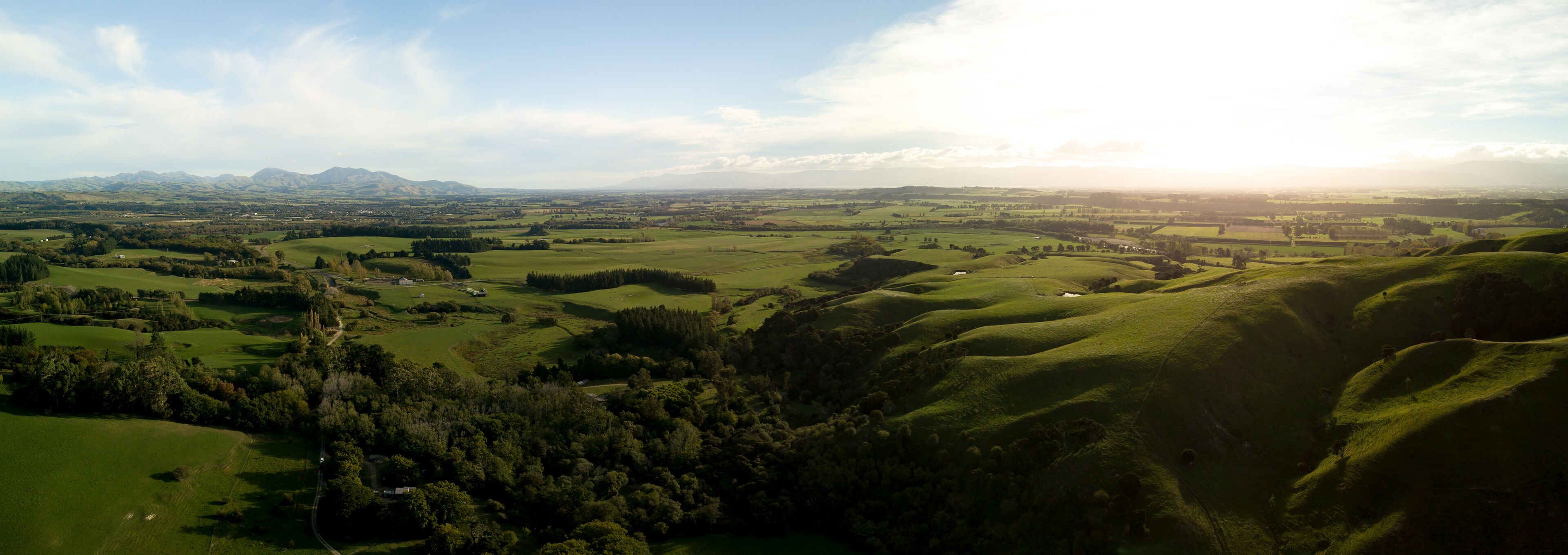 A panoramic view of rolling hills, a distant mountain range, and a small town nestled among the landscape.