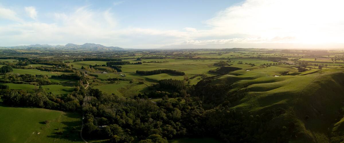 A panoramic view of rolling hills, a distant mountain range, and a small town nestled among the landscape.