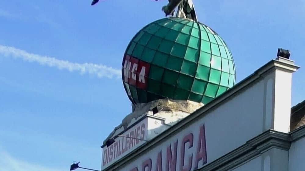 Un bâtiment surmonté d’un globe terrestre et d’une statue d’aigle, portant l’inscription « Fernet-Branca ».
