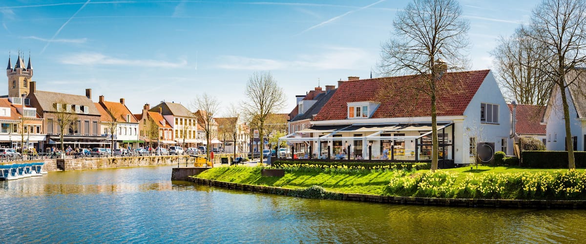 A canal with boats, a bridge, and buildings along the water.