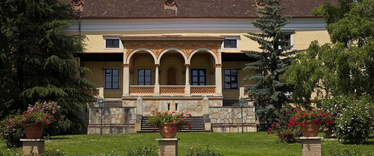 A historic building with a tiled roof, arched windows, and a stone facade.