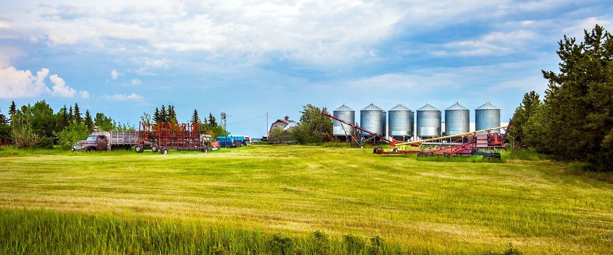A rural landscape with a field, silos, and agricultural machinery.