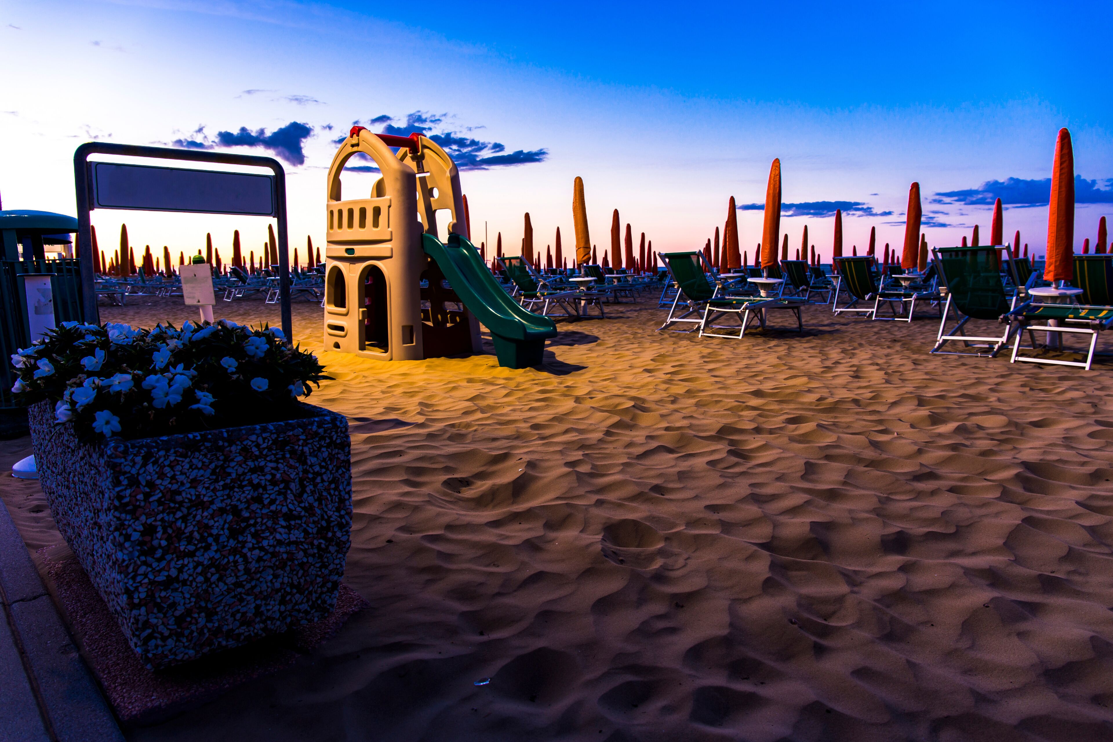 Slide for children on the beach with sunbeds in the background at sunrise time. Jesolo beach, Italy.
