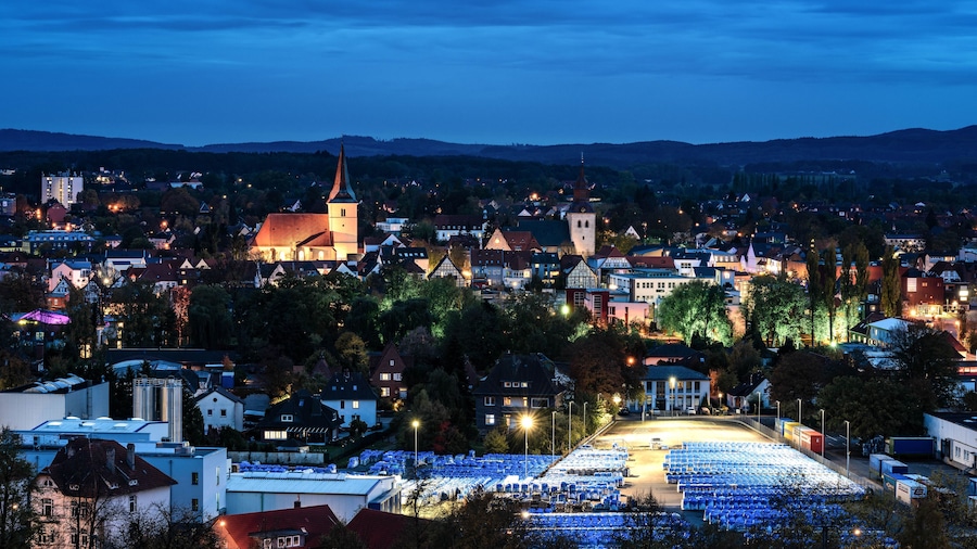 A town at dusk with a prominent church, residential buildings, and a large parking lot.