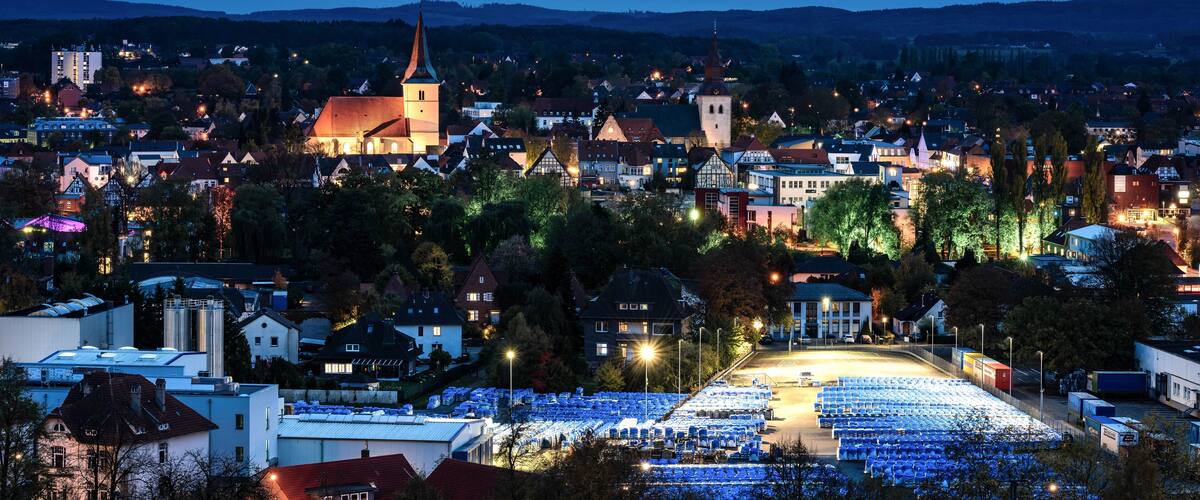 A town at dusk with a prominent church, residential buildings, and a large parking lot.