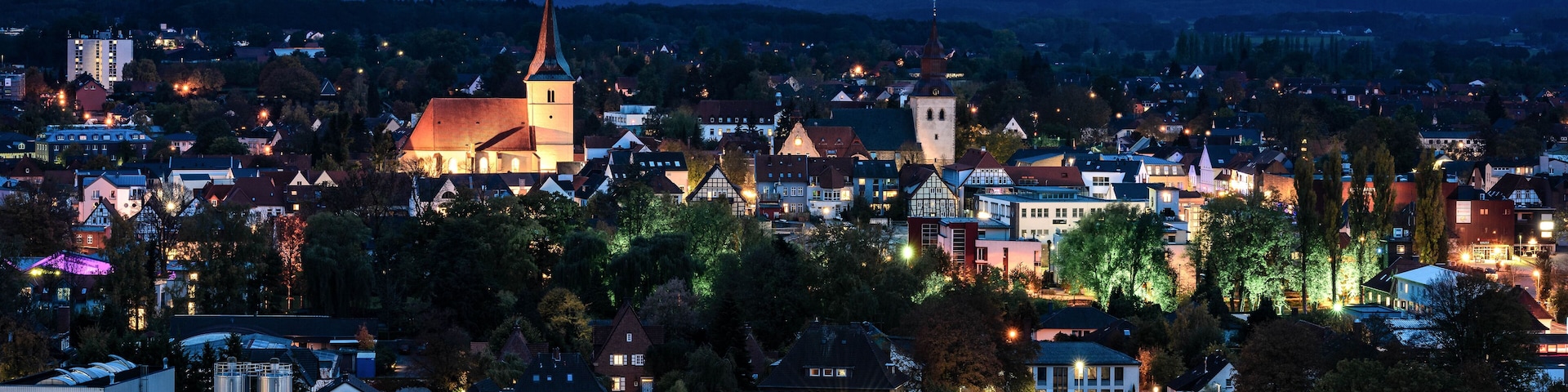 A town at dusk with a prominent church, residential buildings, and a large parking lot.