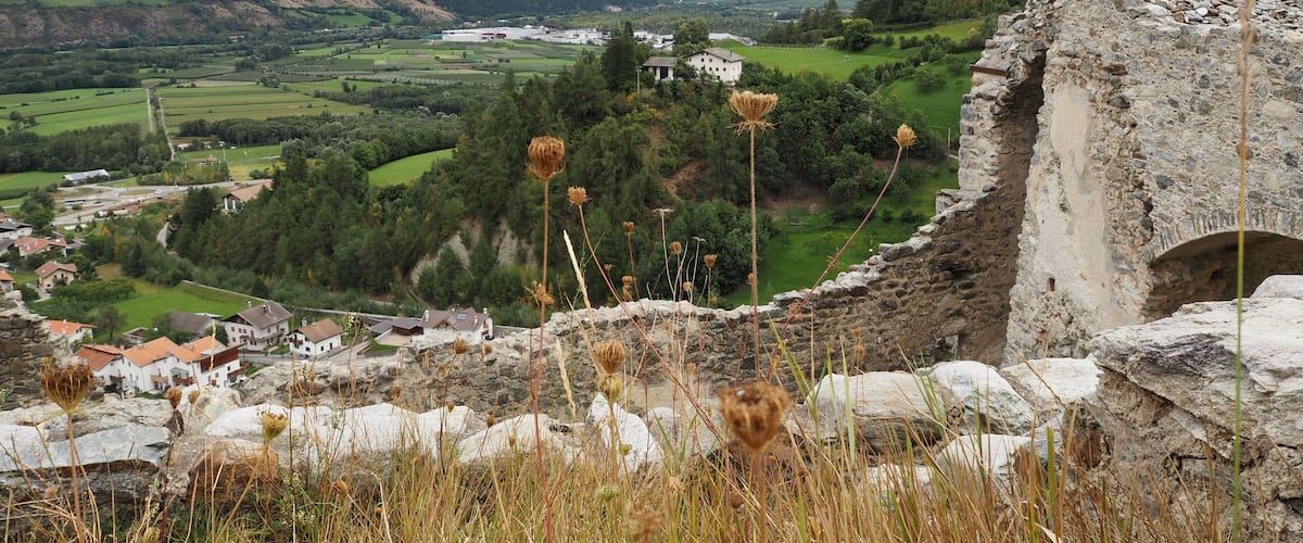 A mountainous landscape with a village, stone ruins, and a church.