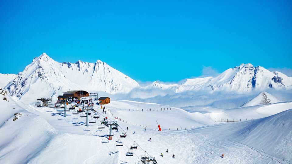 Ski station high in the mountain Les Arcs region of Alps with chairlifts and snow peaks on background