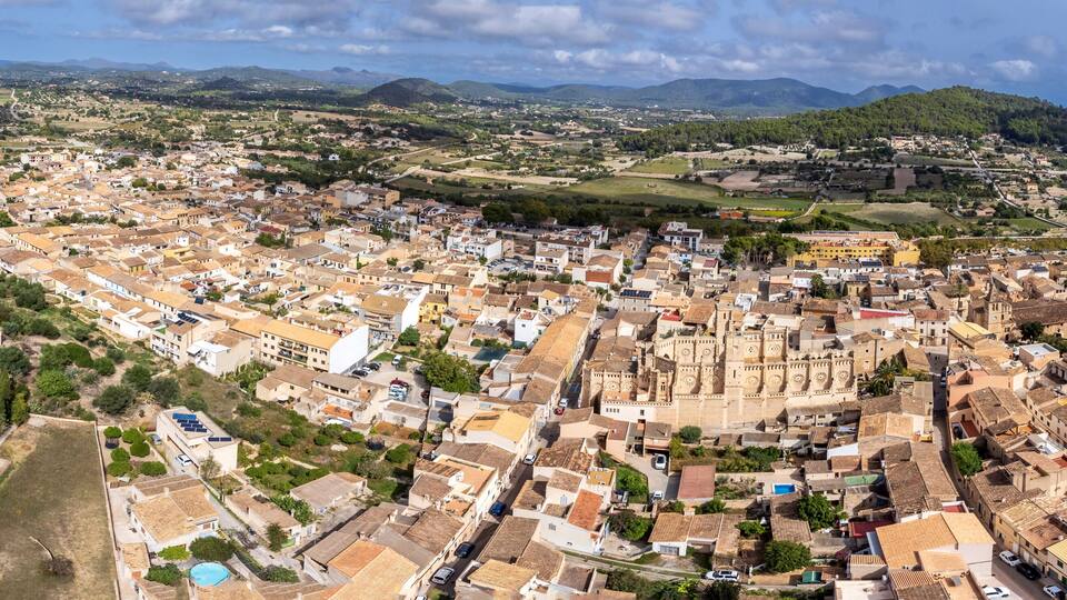 A coastal town with a historic fortress, surrounded by mountains and a coastline.