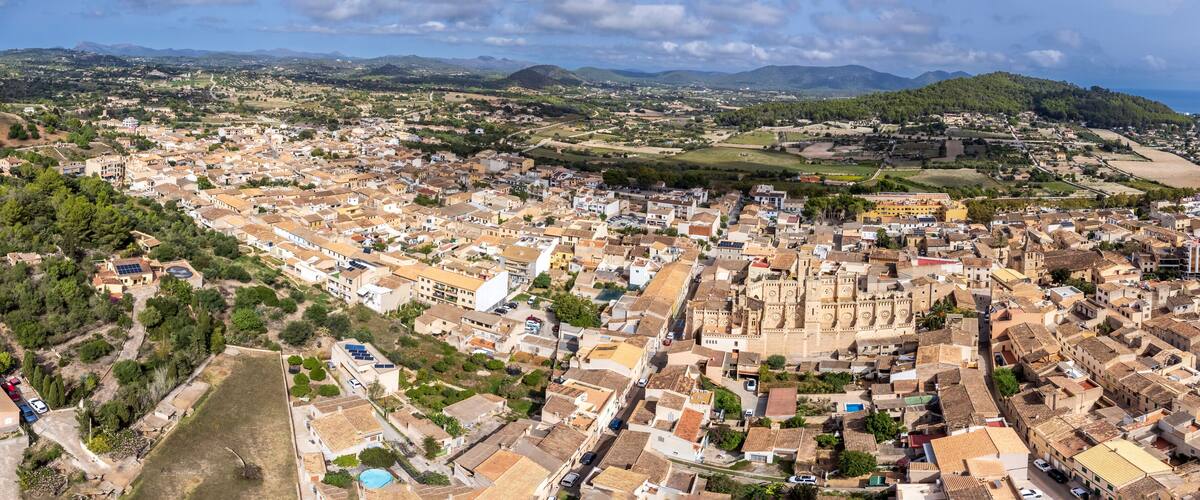 A coastal town with a historic fortress, surrounded by mountains and a coastline.