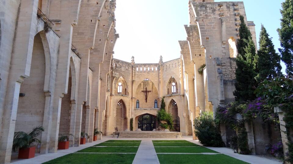 A historic cathedral with a central nave, arched windows, and a cross at the entrance.
