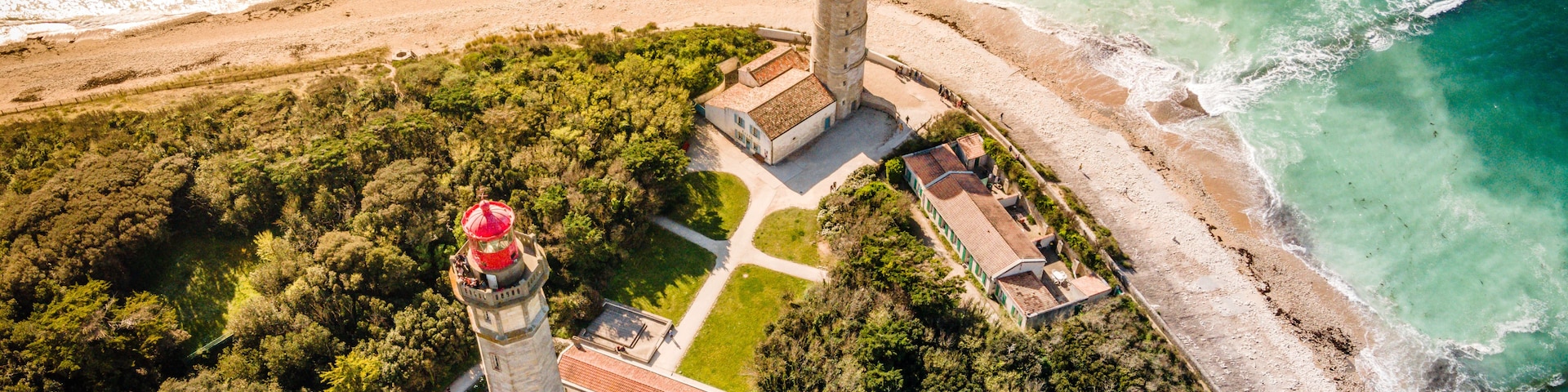 Vista aérea de una zona costera con un faro, una playa y una área boscosa.