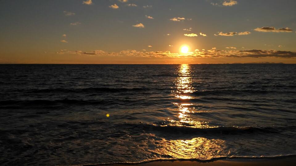 A sunset over the ocean with the sun reflecting on the water.